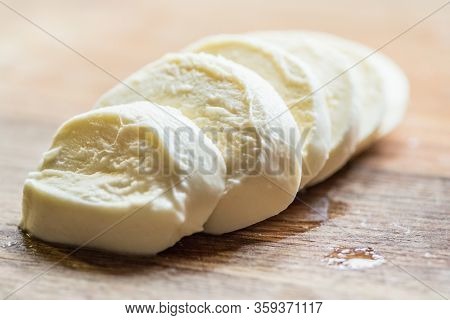 Slices of water buffalo cheese mozzarella on wood background. Close-up.