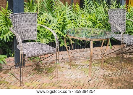 A Vintage Metal Table And 2 Chairs Are On The Outside Of The Coffee Shop, With Ferns And Glass Wall 