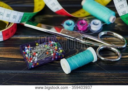Macro Color Photo Of Different Sewing Tools Like Scissors And Sewing Thread On Wooden Table