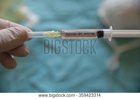 Close Up Shot Of A Syringe With The Word Coronavirus Vaccine.he Is Holding Her Hand With A White Lat