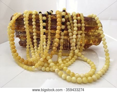 A Lot Of Baltic Amber White Beads Lie On A Large Piece Of Natural Amber. Template For Decorating A J