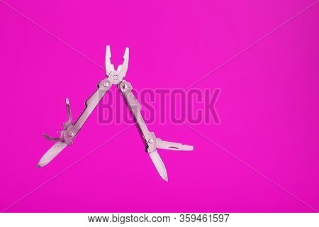 Multitool Is A Multi-functional Tool On A Pink Background. The Concept Of An Open, Flying Multi-tool