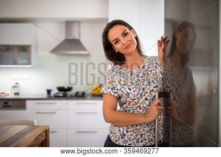 Pretty, young woman in her modern kitchen, by the fridge, about to cook a healthy meel for her family (color toned image)