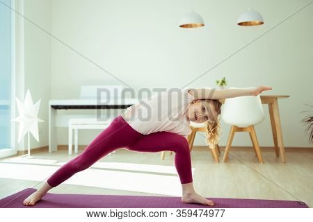 Pretty Happy Child Girl Having Fun Making Yoga Exercises At Home During Coronavirus Quarantine