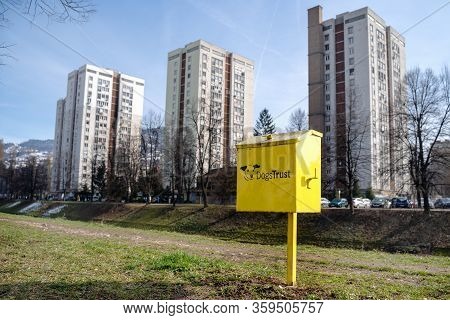 Trash Bin For Dog Refuse Stands In City Park On Green Lawn, High Rise Buildings On The Background. D