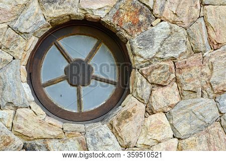 A Round Metal Window On The Stone Wall Of An Unidentified Residence