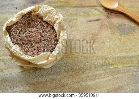 Flax Seeds In Paper Bag On Wooden Table