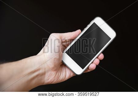 Man Holding Smartphone With Empty Screen Isolated On Black Background. Male Hands With Phone, Space 