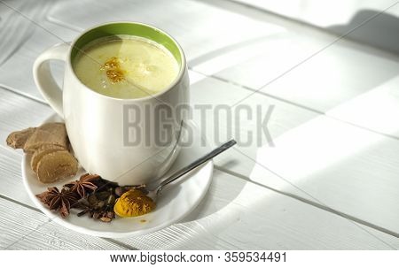 Traditional Indian Drink In A Mug . Turmeric Milk Or Golden Milk With Cloves, Pepper, Cinnamon And T