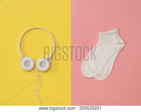 White Socks And White Headphones On A Yellow And Pink Background. The Color Trend. The Concept Of Mu
