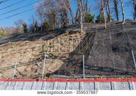 Strengthening The Mountain Slope With A Metal Mesh That Prevents Rockfall On The Road. Abstract Back
