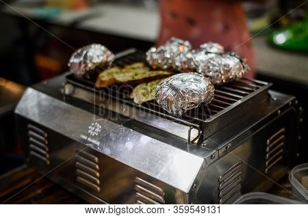 Potatoes In Aluminum Foil Grilling On Bbq, Summer Food