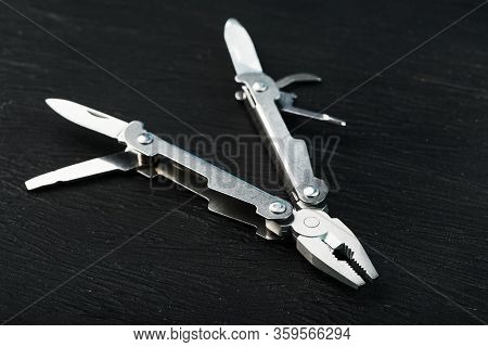 Multitool Is A Multi-functional Tool On A Black Background. The Concept Of An Expanded Multi-tool Wi