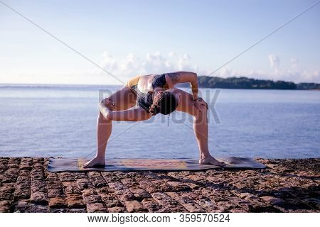 Sunrise Yoga Practice. Young Woman Practicing Parivrtta Utkata Konasana, Revolved Goddess Pose. Open