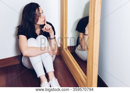 Young Girl With A Bruise And Stitches Under Her Eye Sitting On The Floor In Front Of A Mirror Saying