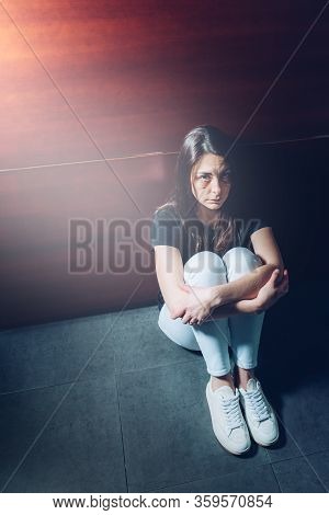 Battered Woman Sitting On The Floor With Her Legs Wrapped Up In Protection