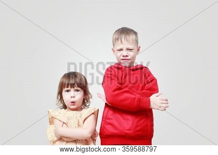 Dissatisfied Children On Gray Background. Brother And Sister Are Annoyed, Angry. Quarrel Of Children