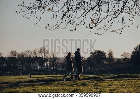 London, Uk - March 22, 2020: Two People With Coffee In Hand Walking In Broomfield Park, Public Park 