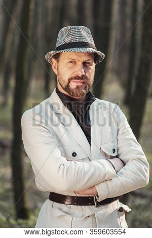 Half-body Portrait Of Confident Presentable Man With Folded Arms Standing In Nature Looking At Camer