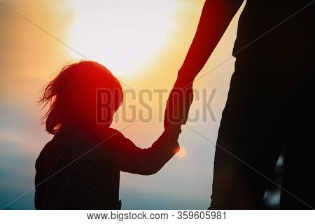 Silhouette Of Mother And Daughter Holding Hands At Sunset