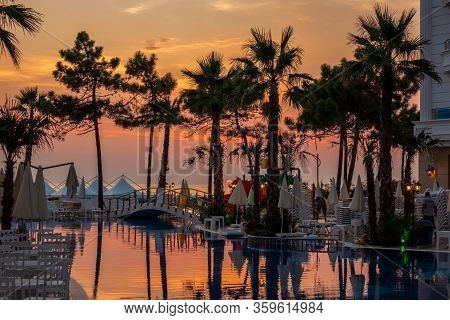 Durres, Albania - August 9, 2018: Beautiful Sunset View Of A Pool Area With Palm Trees, Reflecting P