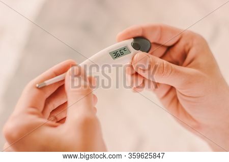 Closeup Of Doctor Looking At Electronic Thermometer With Healthy Normal 36.6 Temperature. Man Patien