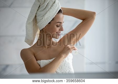 Young Female Using Deodorant After Shower In Bathroom
