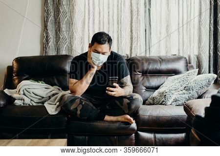 Asian Bearded Man Sit On Couch In Living Room At Home. Looking At Cell Phone.