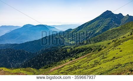 View Over The Green Valley, Surrounded By High Mountains On A Summer Sunset. Layers Of Mountains In 