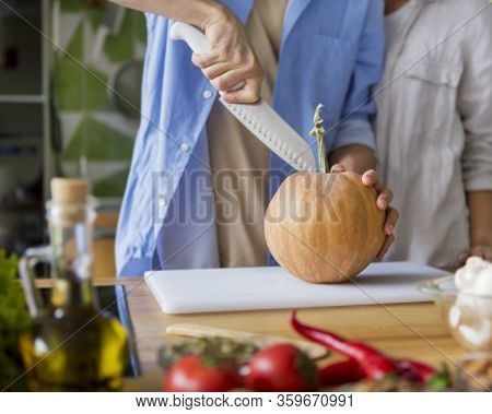 Man Cutting Small Pumpkin For Pie In The Kitchen, Vegetarian Concept