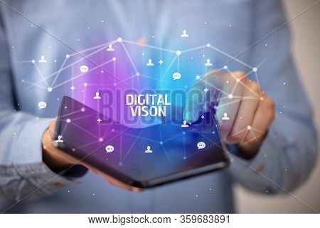 Businessman holding a foldable smartphone with DIGITAL VISON inscription, new technology concept