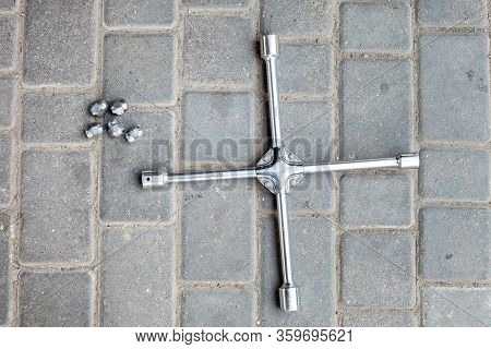 A Cross Wrench With Different Sizes Of Heads For Loosening Wheel Nuts, A Tool For Car Service Lies O