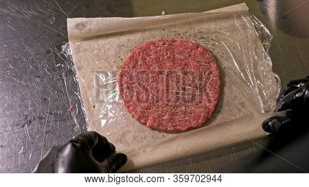 Cook Makes Meat Medallions For Burgers. Chef In Black Food Gloves Makes Cutlet. Cutlets Are Leveled 