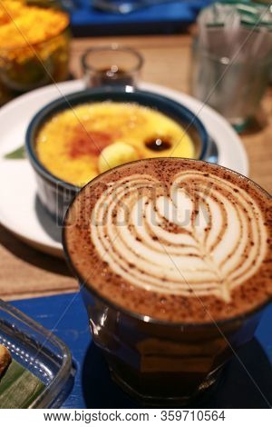 Latte Art On A Cup With Vanilla Crème Brûlée Dessert On The Background.