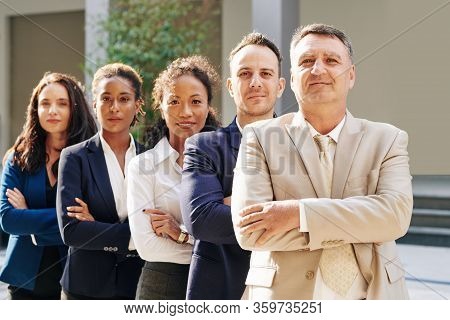 Confident Mature Entrepreneur And His Business Team Standing One Beding Another And Looking At Camer