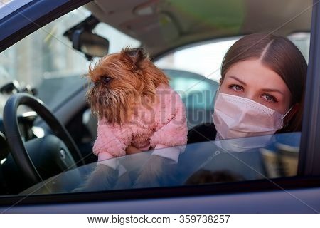 Girl In White Medical Gauze Mask In The Car With A Dog In Sunny Spring Day. Protection Against Disea
