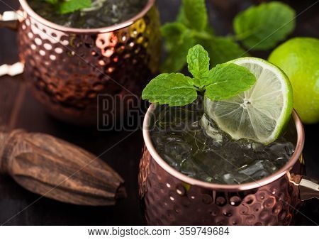 Moscow Mule Cocktail In A Copper Mug With Lime And Mint And Wooden Squeezer On Dark Wooden Table Bac