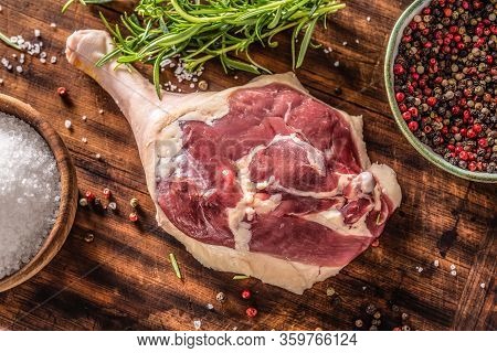 Top Close-up View Of A Raw Unskinned Duck Leg Surrounded By Pepper , Rosemary Herb And Salt On A Dar