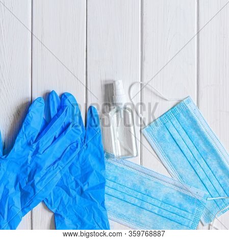 Medical Protective Mask, Rubber Gloves, Antiseptic And White Anti-irus Tablets Lie On A White Wooden