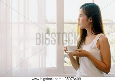 Young Asian Woman Having A Cup Of Coffee. She Stay Isolation At Home For Self Quarantine. Corona Vir