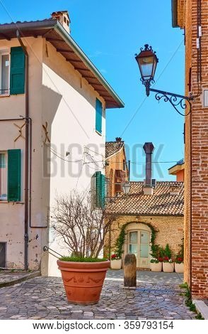 Old street with big flowerpot in Santarcangelo di Romagna town, Rinini Province, Italy. Italian cityscape