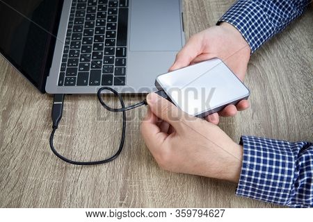 Male Hands In Blue Checked Shirt Disconnect An External Hard Drive From The Laptop.
