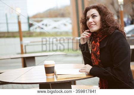 A Very Pretty Woman Laughs Merrily While Reading A Fascinating Book On The Terrace Of A Street Resta