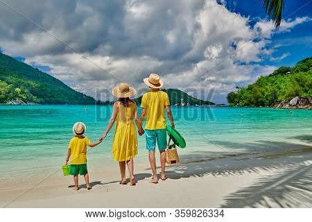 Family on beach, young couple in yellow with three year old boy. Summer vacation at Seychelles. Port Launay, Mahe. 