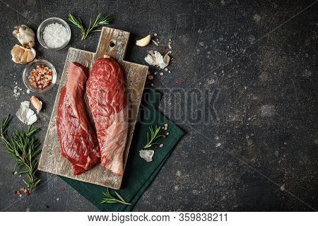 Raw Fresh Steak Sirloin Flap Served With Rosemary, Garlic And On Wooden Cutting Board. Black Angus B