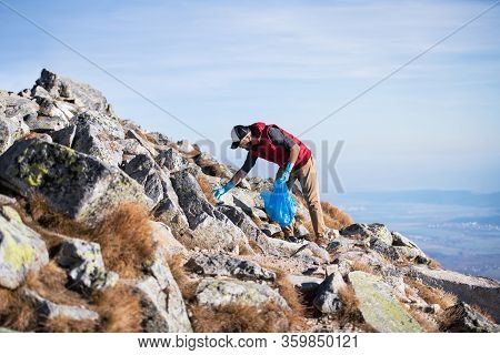 Man Hiker Picking Up Litter In Nature In Mountains, Plogging Concept.