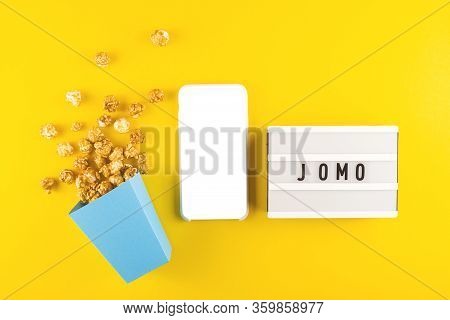 Abbreviation Word Jomo Written On A Decorative Board On A Bright Yellow Background. Next To Mock Up 