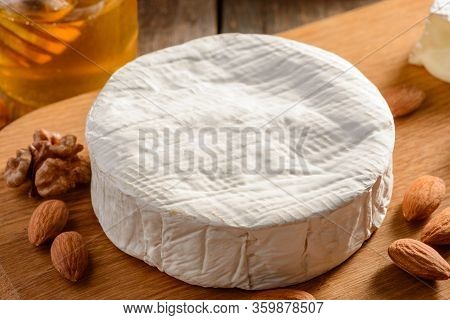 Closeup On A Camember Cheese Wheel And Almonds On Wooden Background
