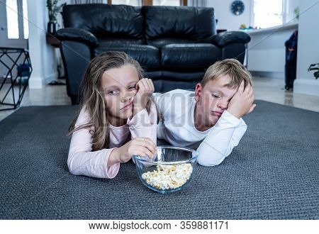 Coronavirus Lockdow. Bored Little Girl And Sad Boy Watching Tv In Isolation At Home During Quarantin
