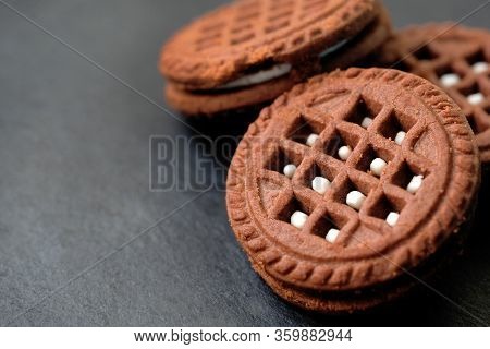 Close Up Round Chocolate Chip Cookies With White Filling. Chocolate Friable Cookies On A Black Backg